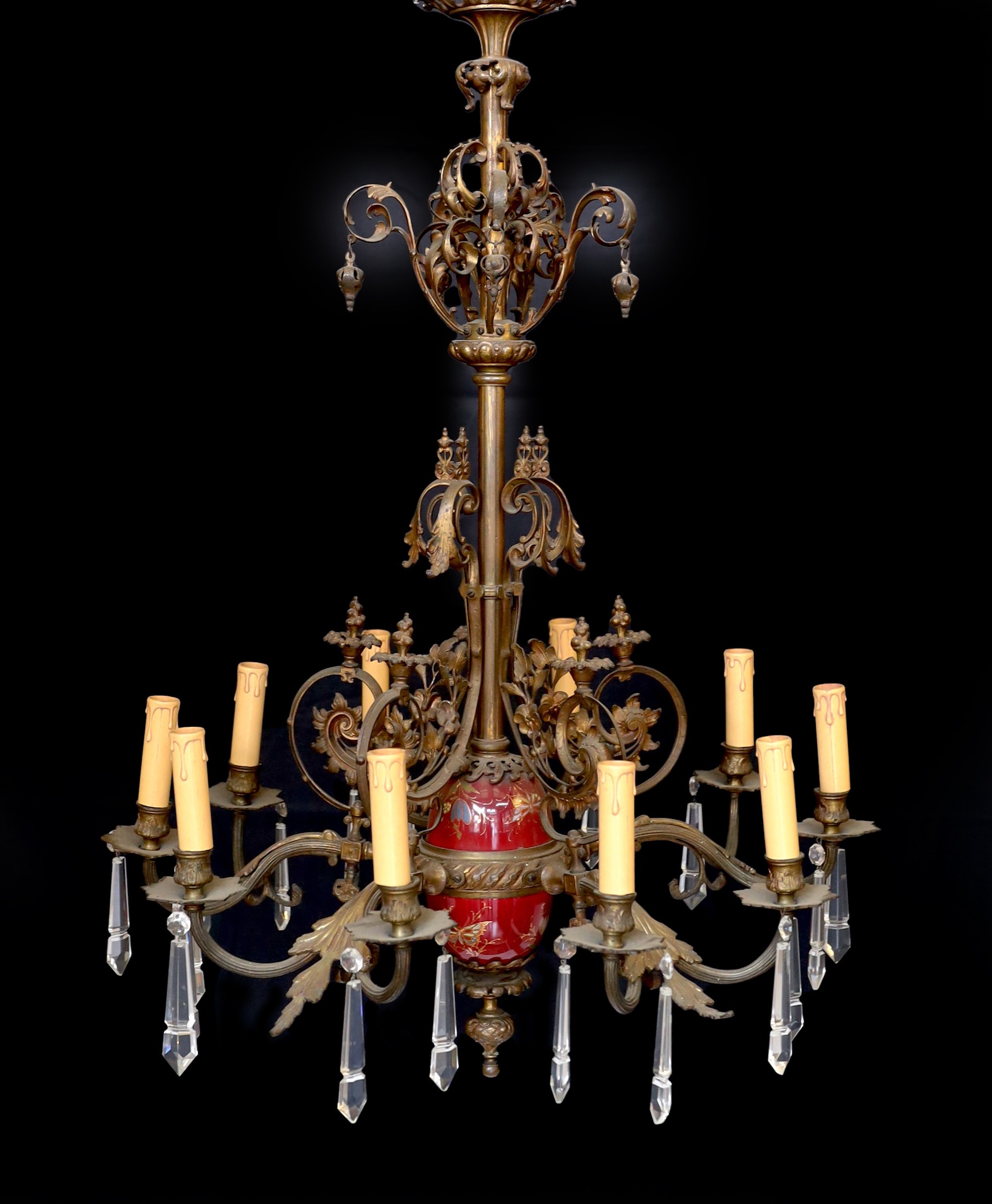 A Victorian bronze ten light gasolier with ornate scrolling foliate frieze and central ceramic stem, hung with spear shaped drops, later fitted for electricity, height 92cm. width 60cm